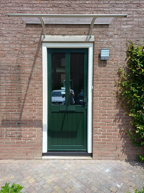 Vooraanzicht van de kunststof deur met dennegroene buitenzijde.